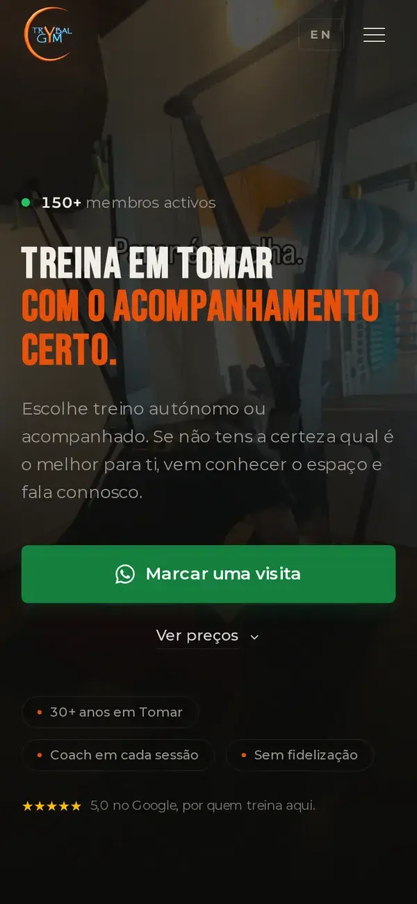 Tribal Gym homepage on a phone with a WhatsApp button to book a visit.